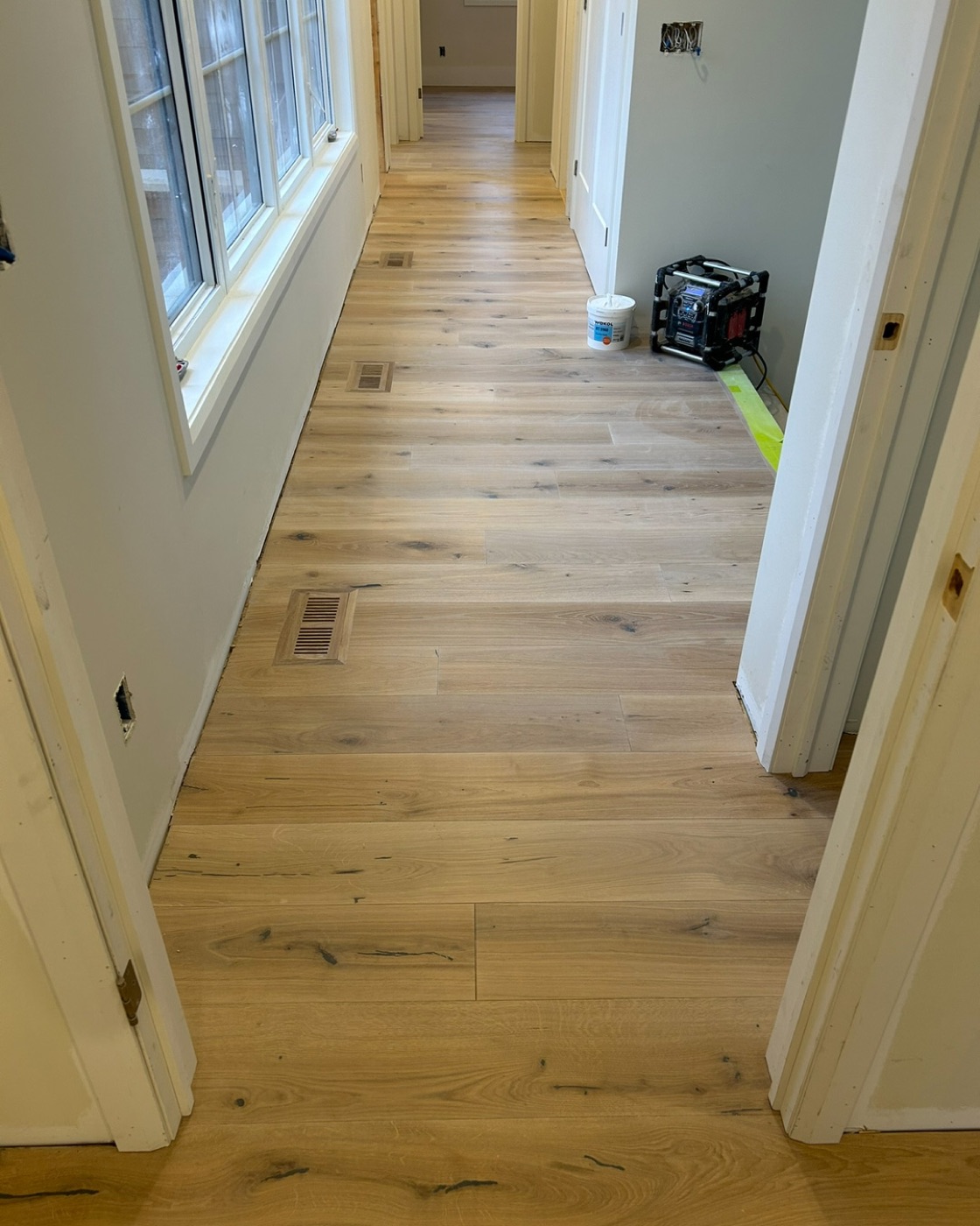 Wide plank hardwood flooring installed through a bright residential hallway